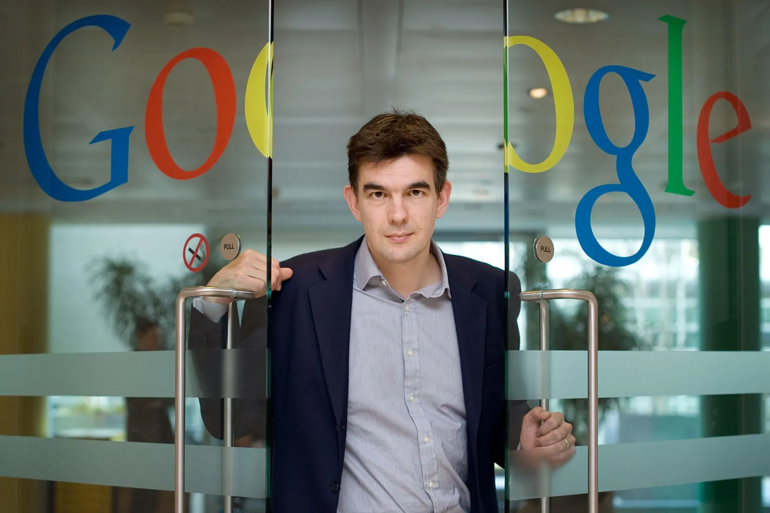 Shutterstock Matt Brittin in a suit in 2009 walking through a pair of glass doors with a large Google logo across them