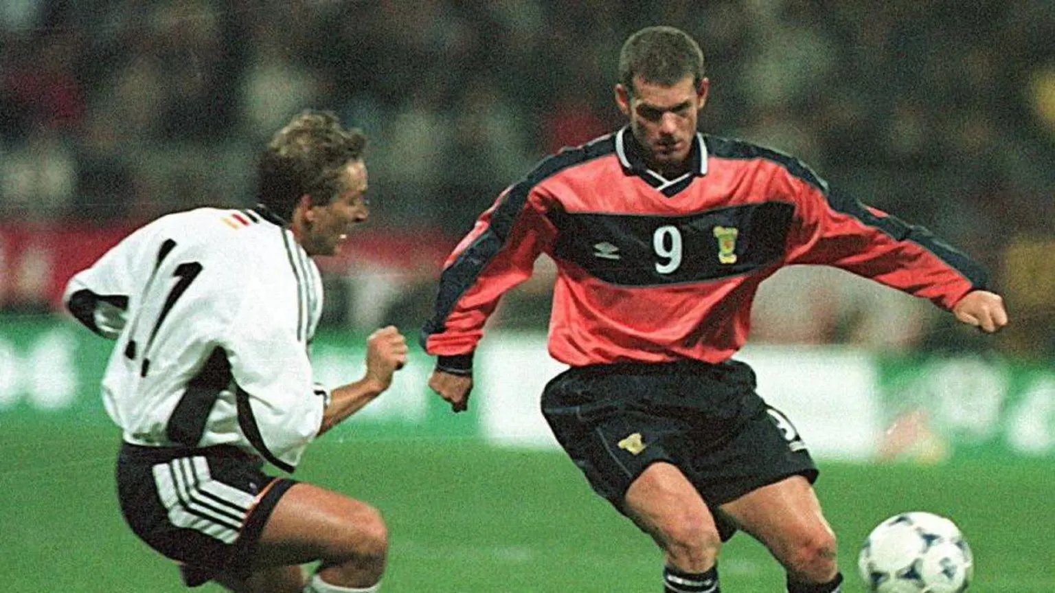 SNS Scotland's Ian Durrant in action against Germany. He is wearing a salmon-pink shirt and black shorts. 