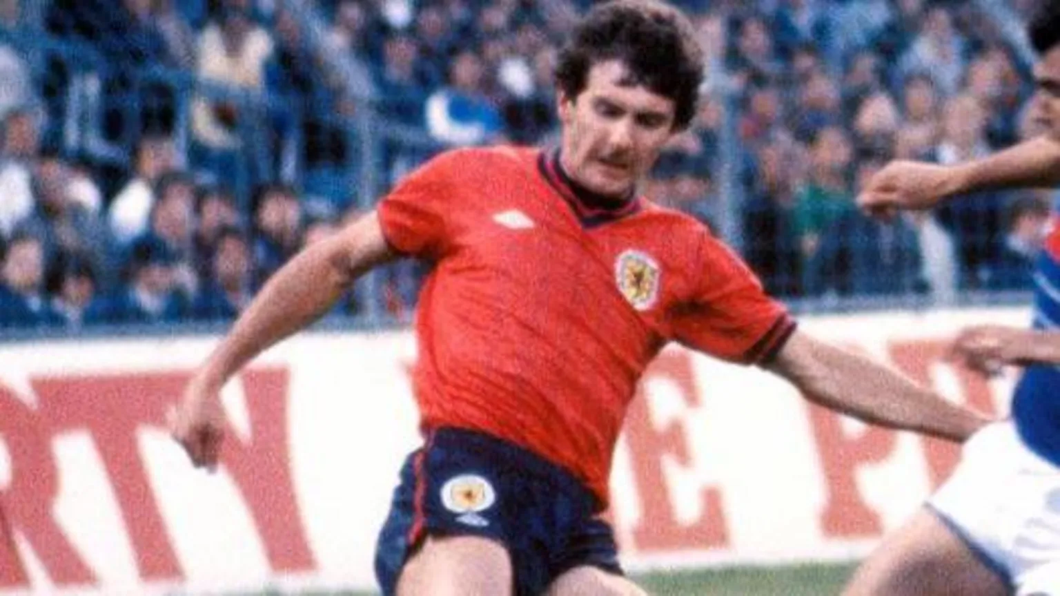 SNS Scotland player wearing red and navy blue shirt and blue shorts.