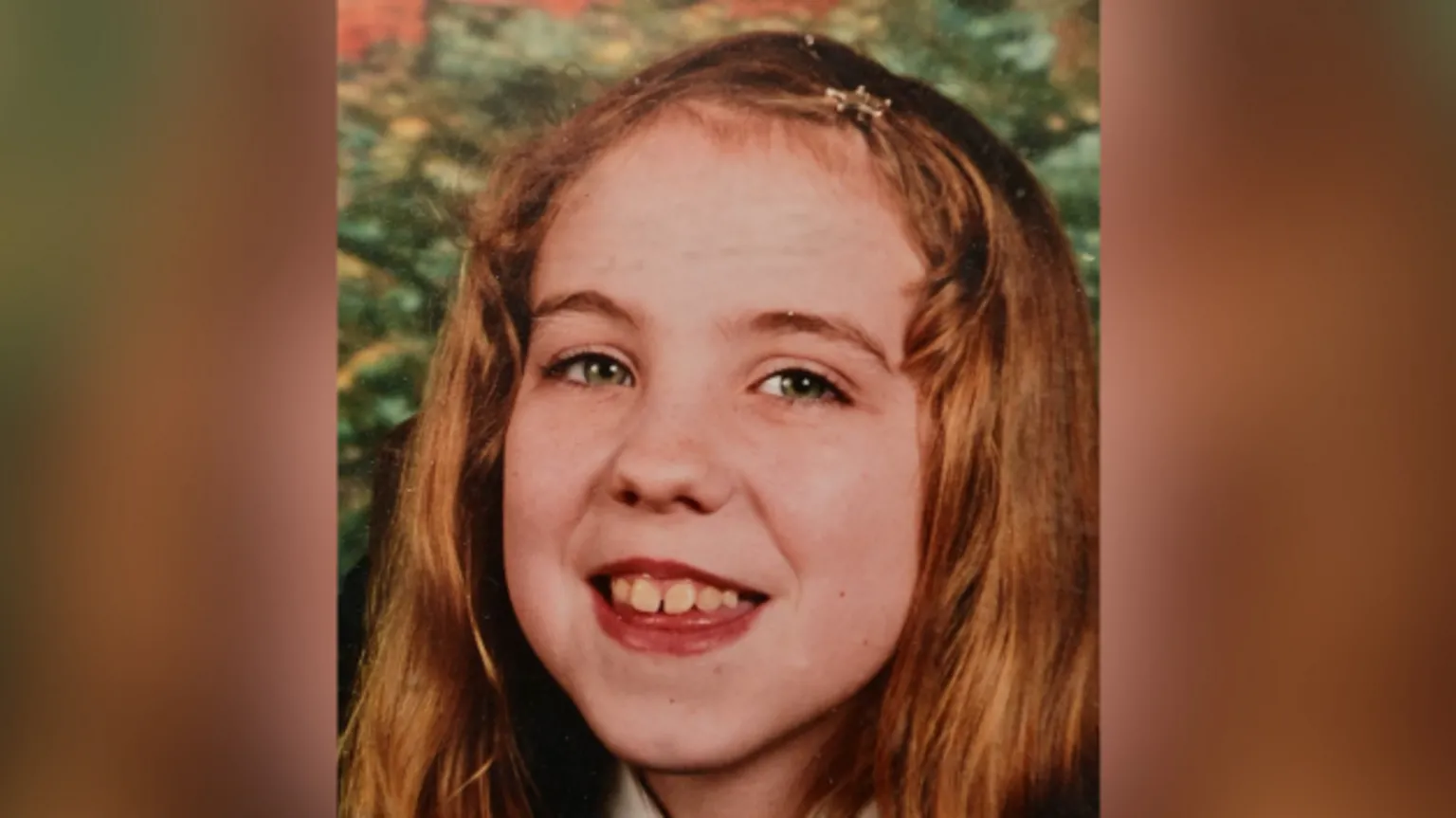 Family handout A childhood photo of a young Natalie McNally smiling at the camera. She has long, reddish blonde hair held back from her face with a clip. 