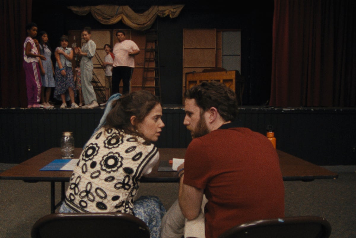 A man and a woman sitting at a desk in a theatre