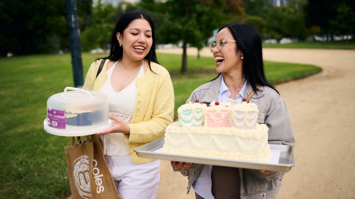 Two women carrying cakes in a park share a laugh