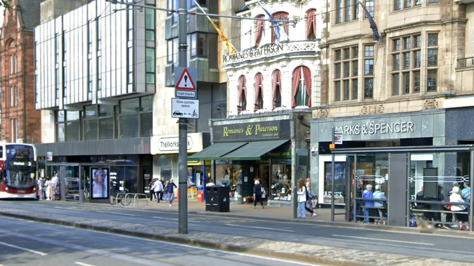 Google The road is in the foreground. The shops of Princes Street is in the background. There is Marks & Spencer and Romanes and Paterson.