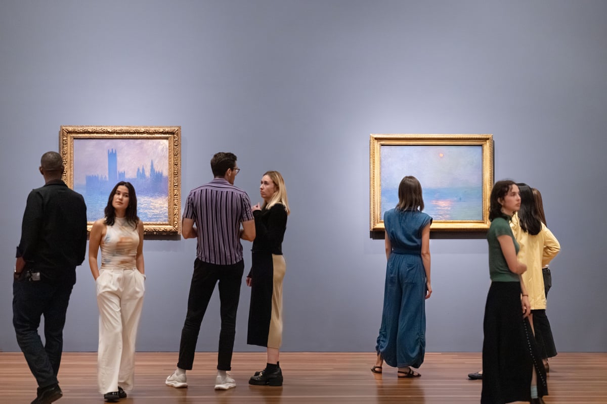 people stand by paintings on wall at museum