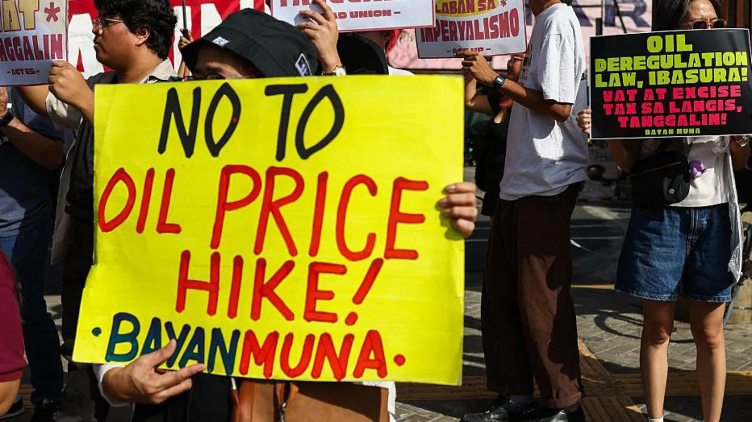  Protesters gather for a rally at a bus station in the Philippines, with one holding a sign saying 