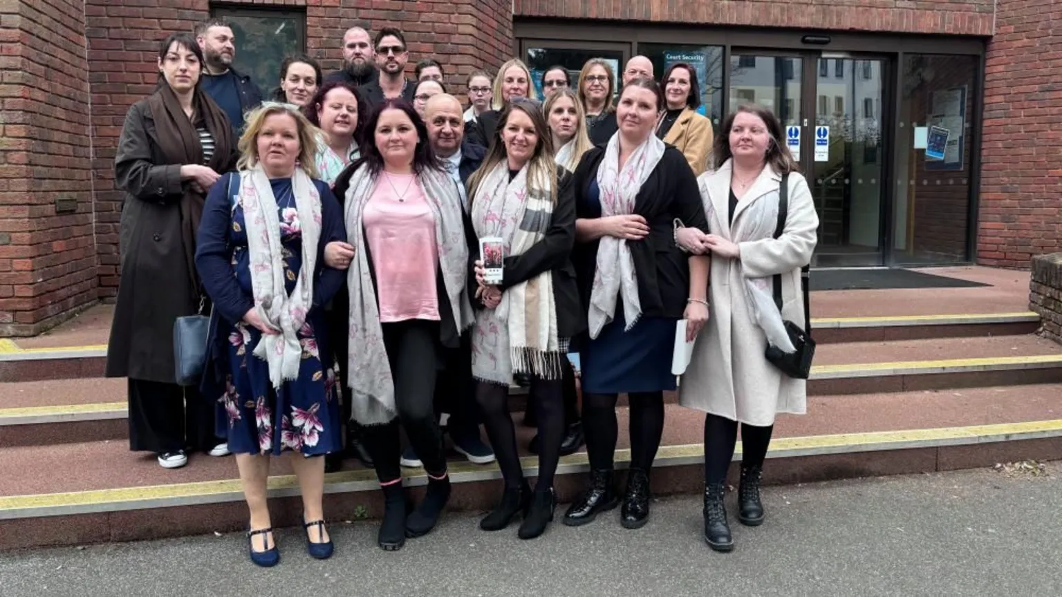 Brian Farmer/BBC A group of people gathered on the steps of Aylesbury Crown Court - a red-bricked building with black-framed entrance doors.