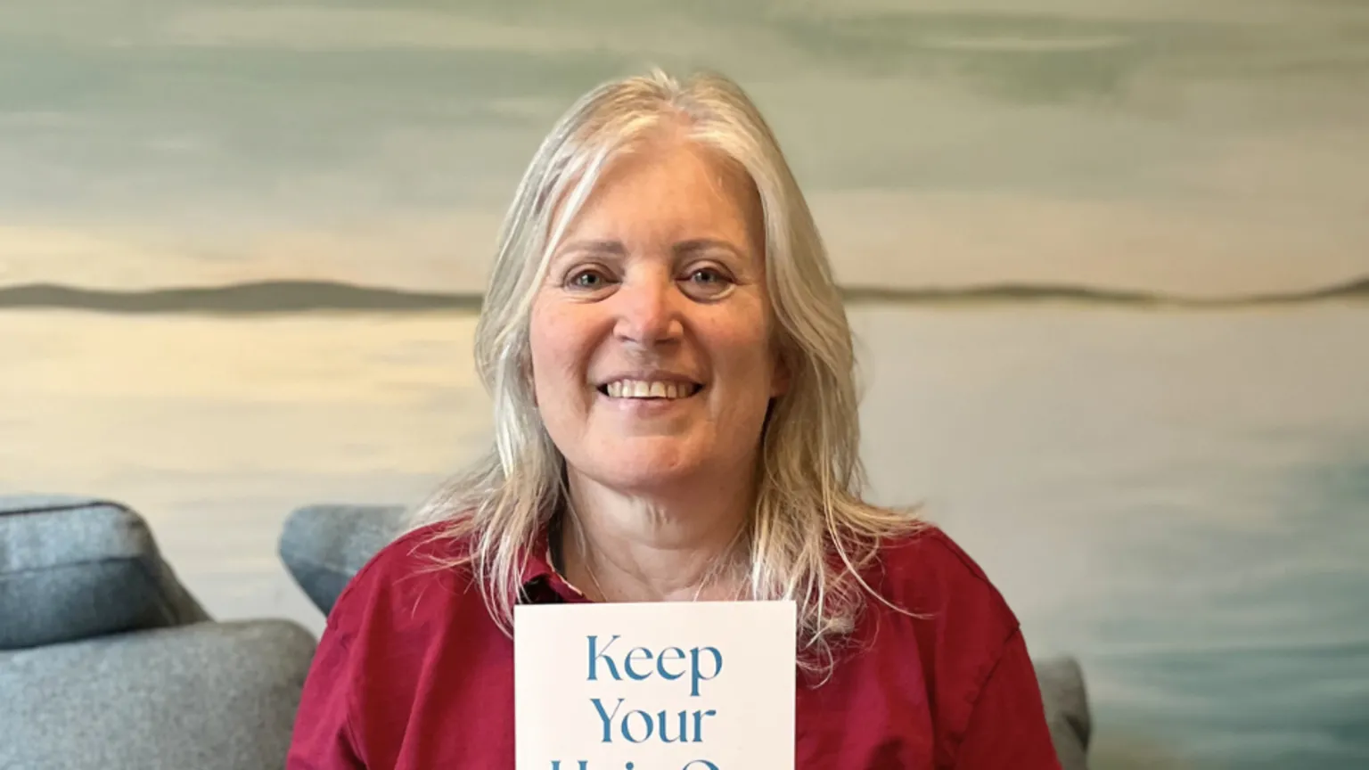 Clare Mackay Professor Clare Mackay smiling at the camera holding a copy of her book 