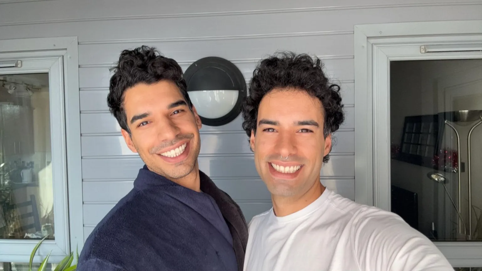 Twin 30-something brothers Riccardo and Simone, with dark brown hair and dark brown eyes, stand next to each other and grin at the camera 