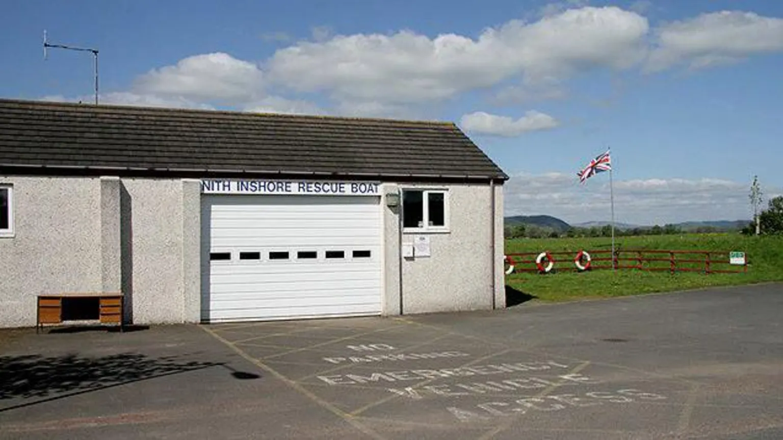 Walter Baxter The Nith Inshore Lifeboat station with a white door and Union Jack flying beside it