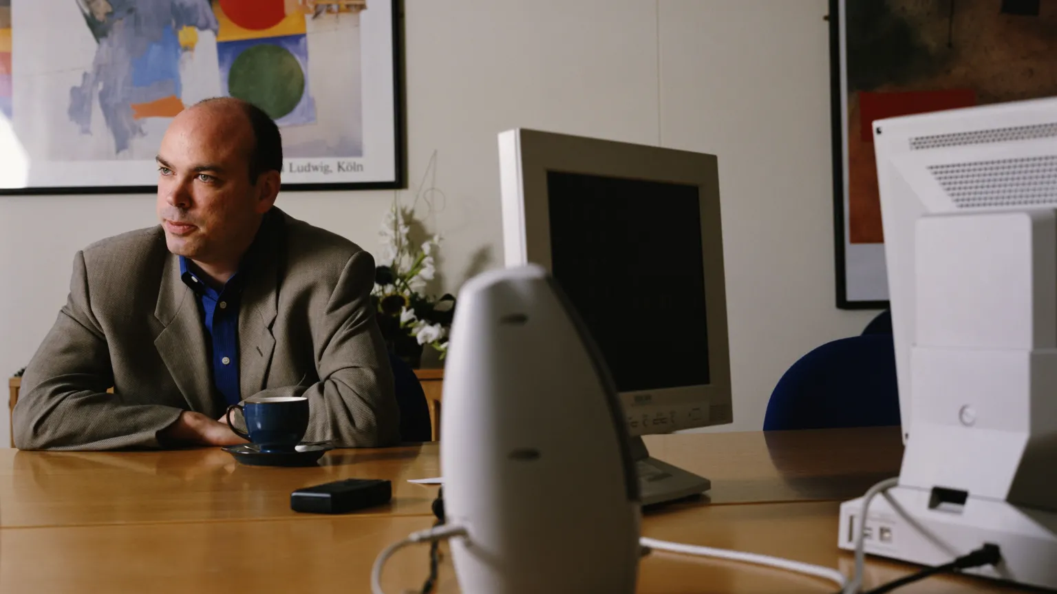  Man at a desk with computers and pictures on the wall