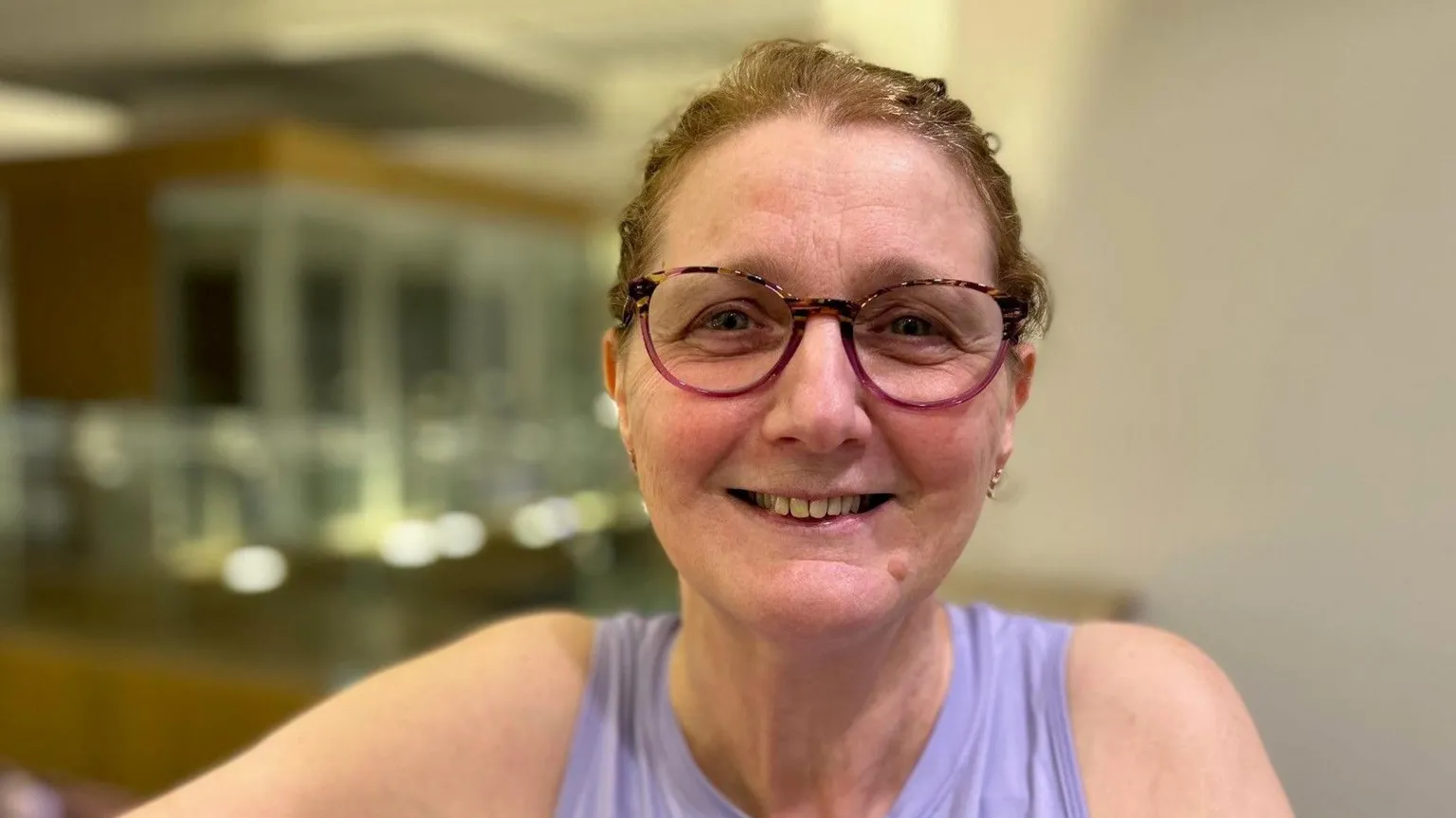 BBC/Helen Richardson Kate is wearing gym clothes and has her hair tied in a ponytail. She is wearing pink-rimmed glasses.