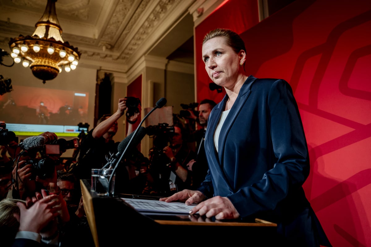 Politician Mette Frederiksen stands at a lectern and delivers a speech with journalists and photographers in front of her