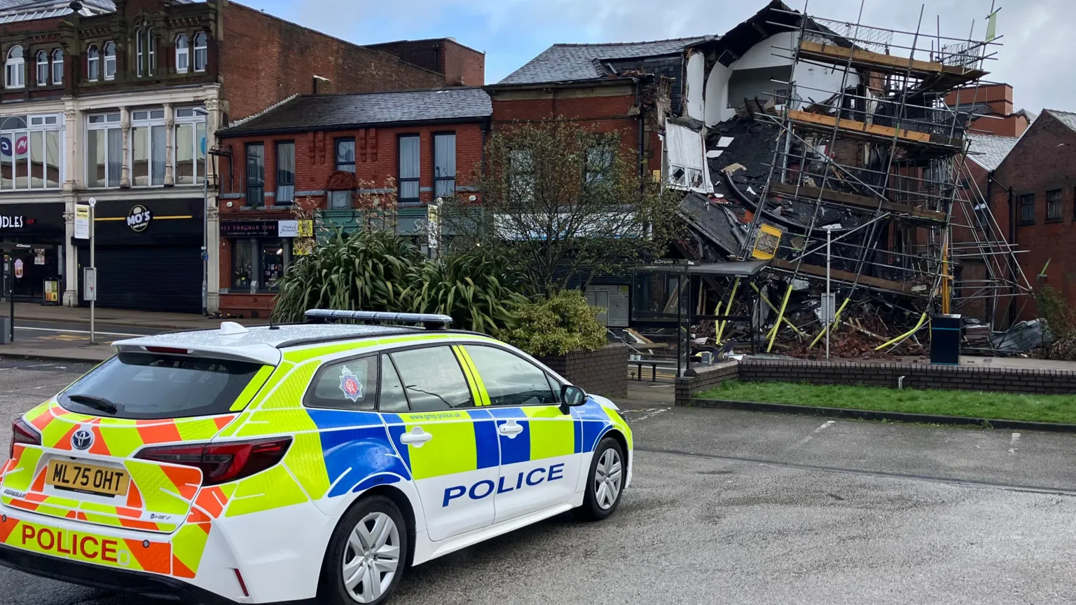 Mat Trewern/BBC A police car is parked across the road from the collapsed building.
