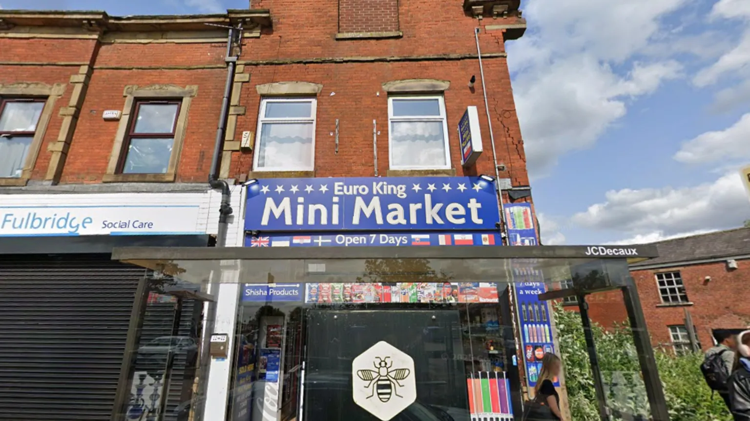 Google Maps Street view of a shop front. It is a convenience store. The sign reads: 'Euro King Mini Market, Open 7 Days' is visible behind the sheer screen of a Bee Network bus shelter.