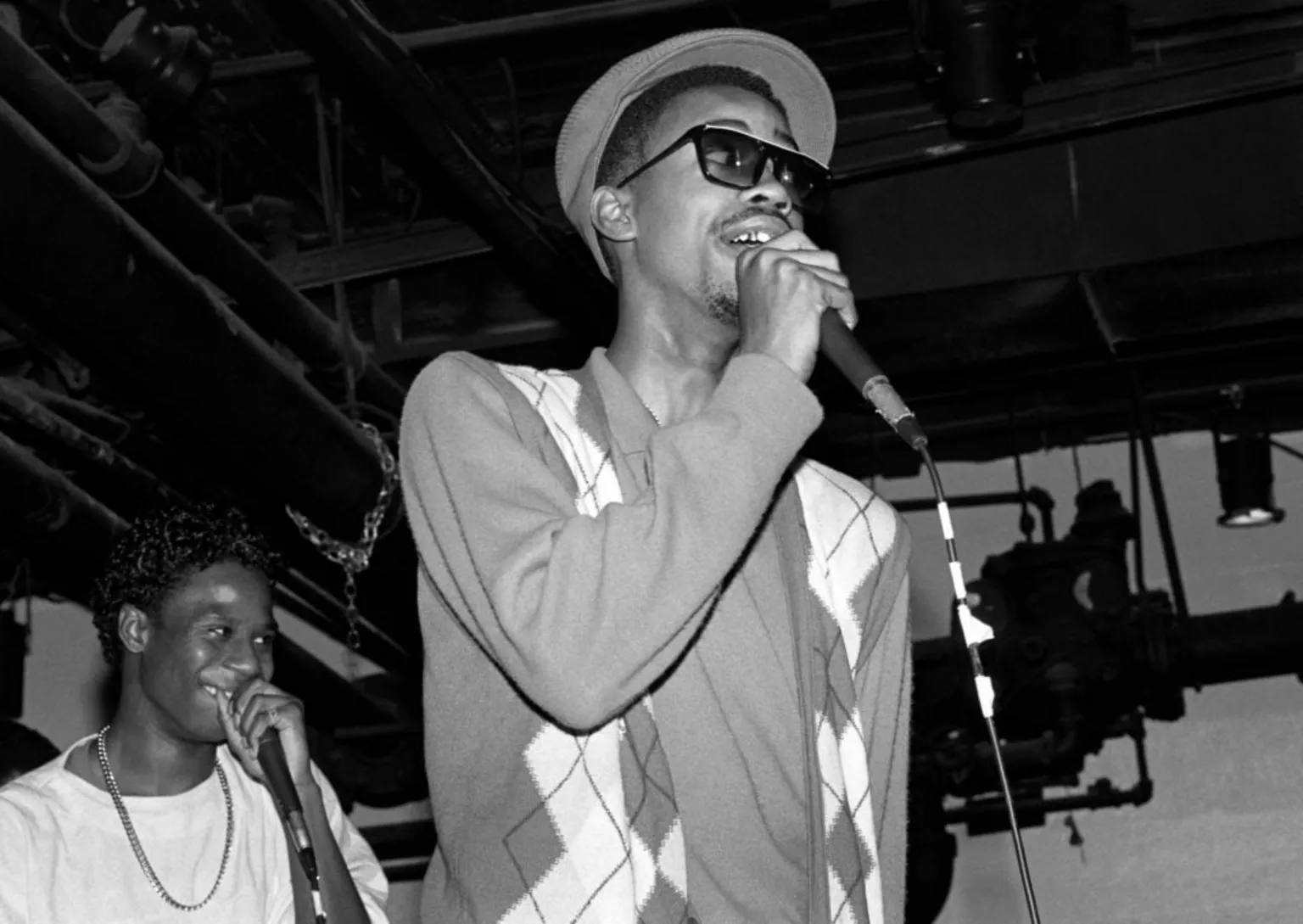  A black and white photo depicts Slick Rick on stage at the start of his career in the 1980s