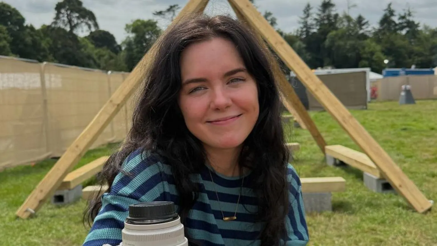 Livi Creighton Coles is smiling at the camera. She is wearing a blue and navy striped top and has long black hair.