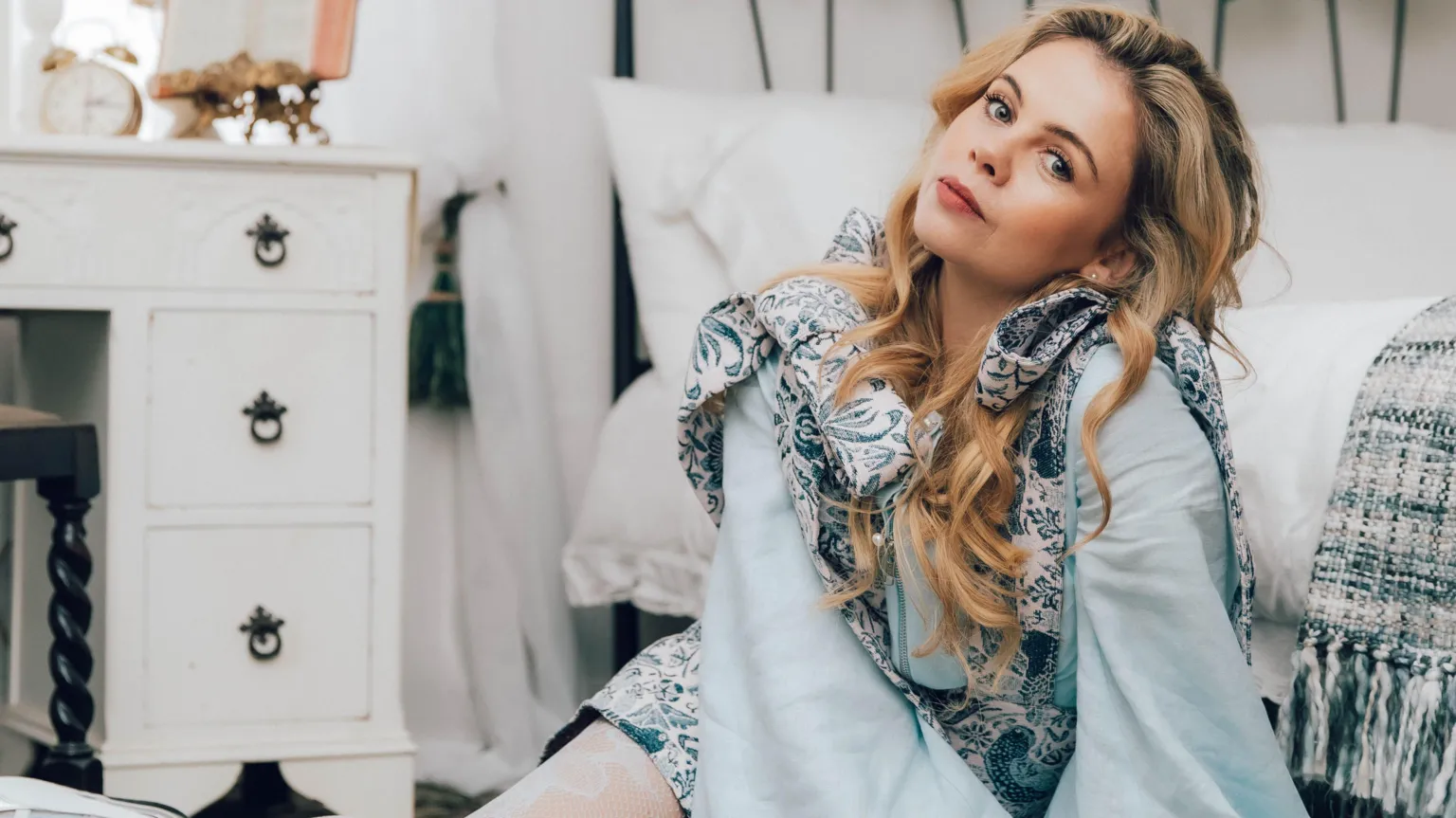 Bryony Coles Saoirse-Monica Jackson has long blonde curly hair. She is wearing a flowing light blue blouse.