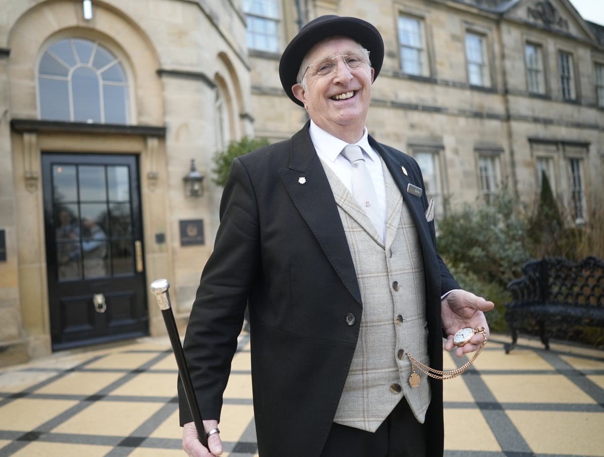A man in a three-piece suit and holding a pocket watch standing outside Grantley Hall