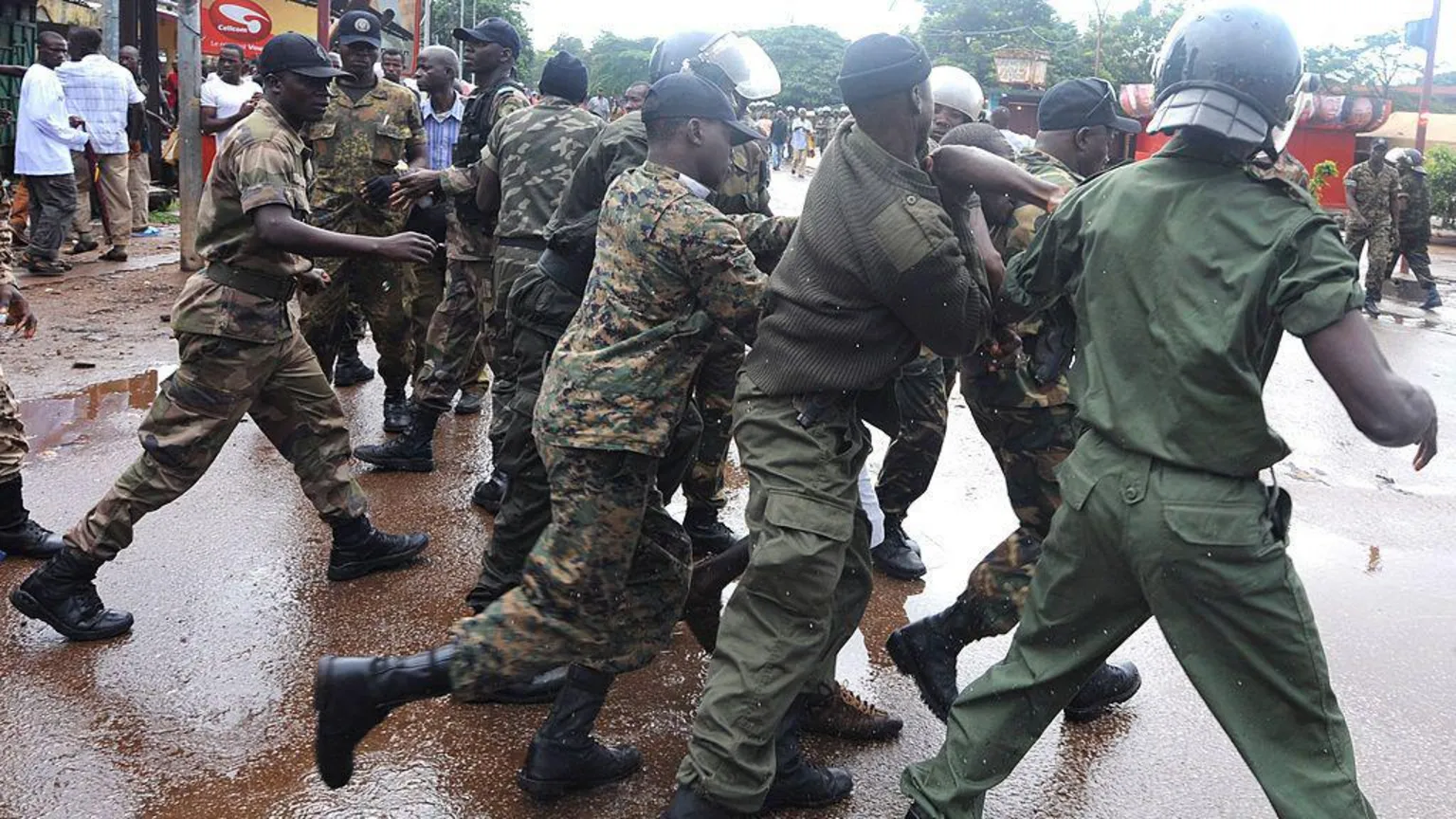 AFP via Police standing in a line - with their backs to the camera - pushing against protesters 