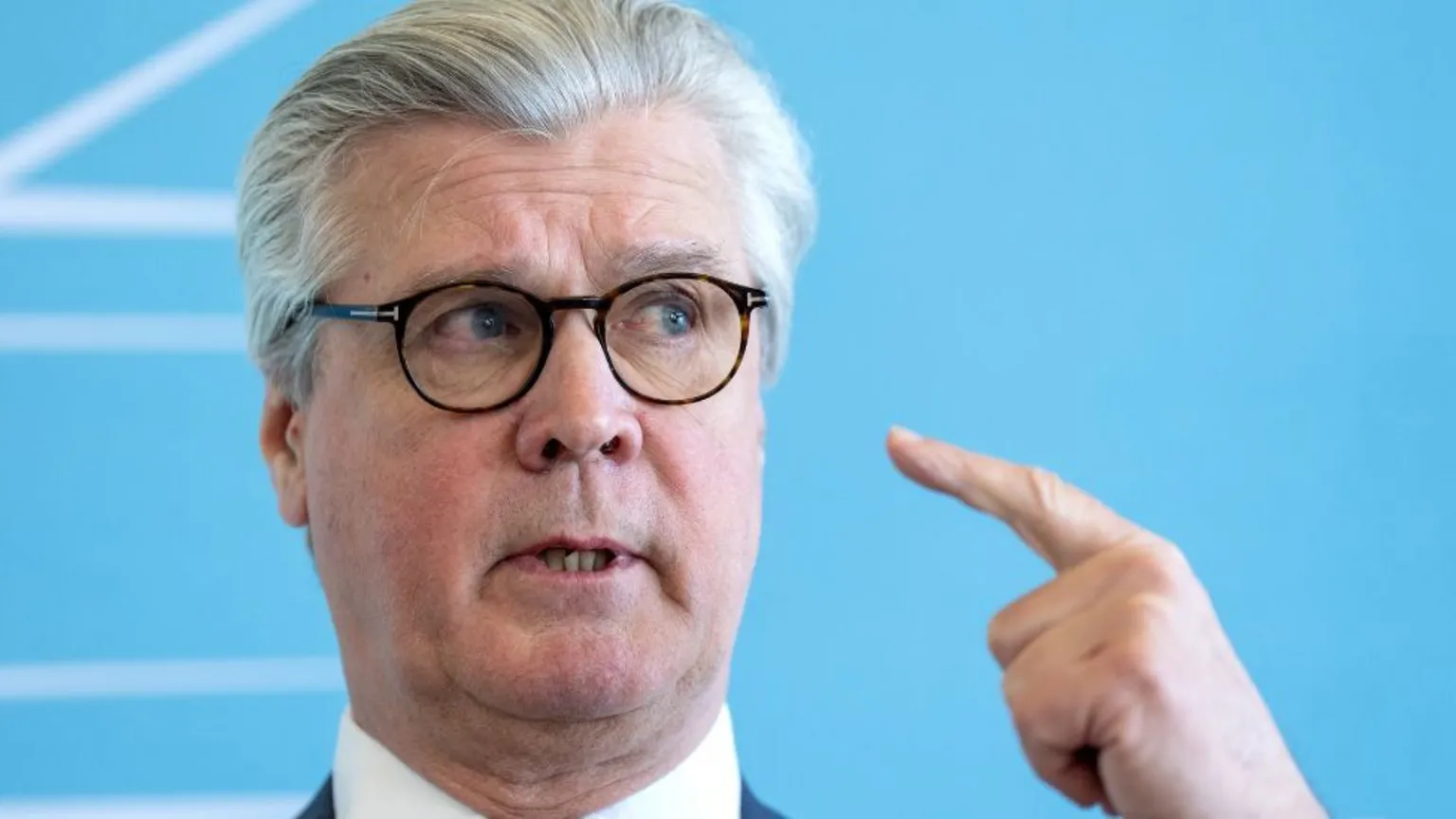  Malcolm Offord, who has grey hair and glasses, in a close-up shot in front of a blue background 