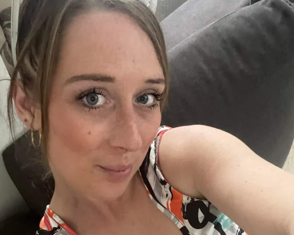 A selfie of a young woman in a summery top. She is half smiling.