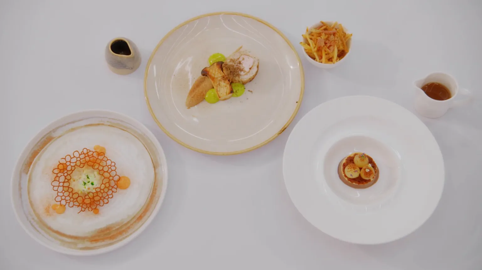 BBC/Shine TV The three dishes of Baty's winning menu. They are all served on white plates, alongside two jugs and a small bowl of chips.