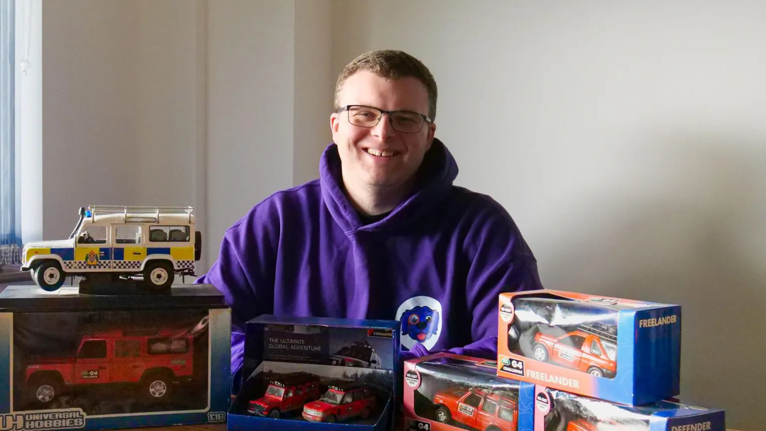 Valart Ltd A smiling man sat behind his collectibles of Land Rover models.