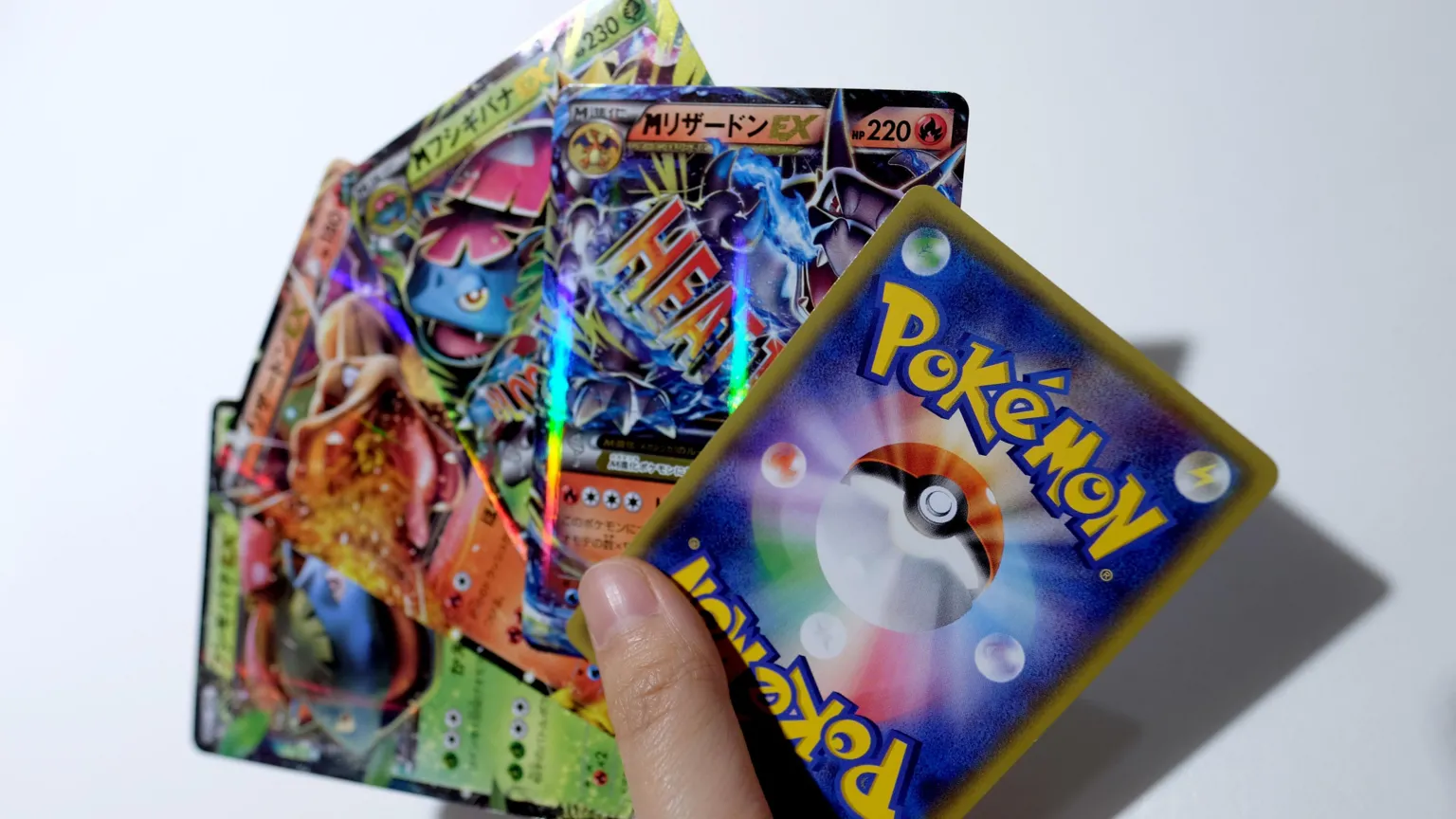  A handful of Pokémon cards being held in a fan-shape, against a white backdrop.