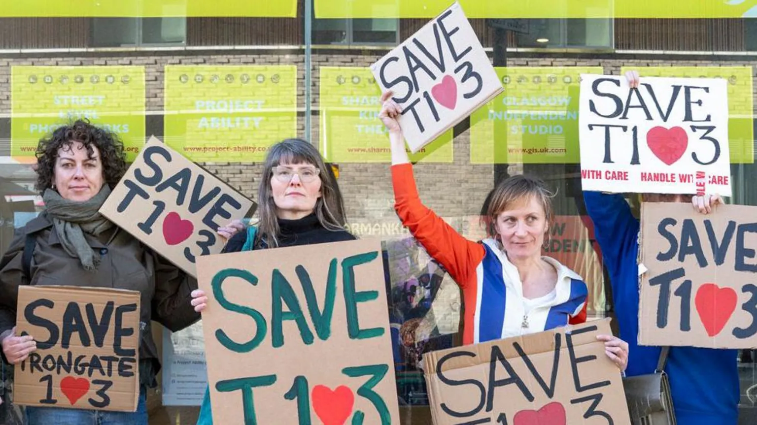 Kirsty Anderson A group of protestors standing outside an art gallery type building. They are all holding signs protesting against possible closure.