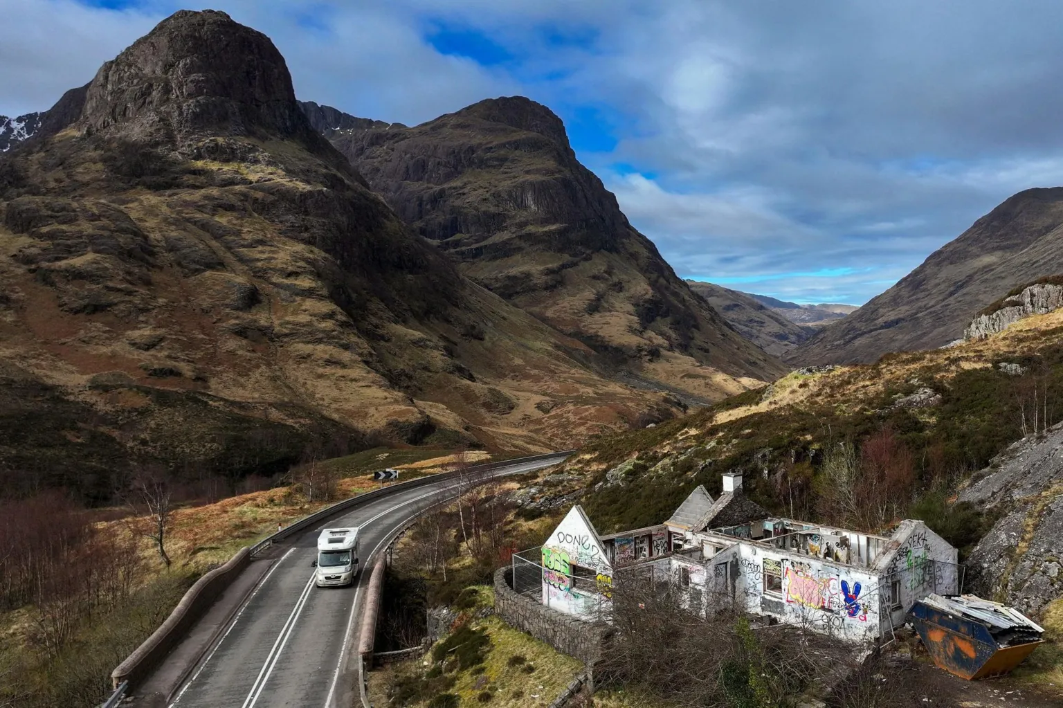  The cottage sits above the A82 in a dramatic mountain landscape. The property's white walls are covered in graffiti. 