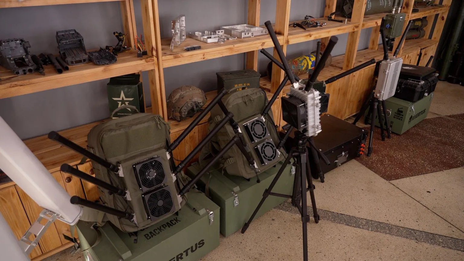 Green anti-drone military equipment leans against a brown wooden shelving unit