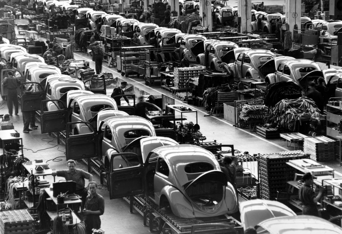 Black and white photo of assembly line of VW Beetles