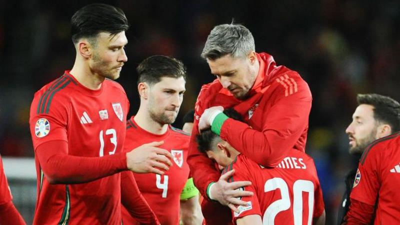 Dan James (centre-right) being consoled by his Welsh teammates.