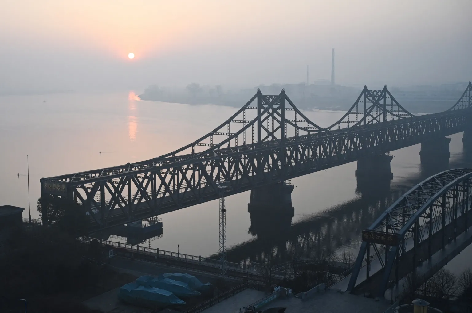 AFP via A recent picture of the sun rising over the North Korean town of Sinuiju, behind the Sino-Korean Friendship Bridge (left) and the Yalu River Broken Bridge (right), as seen from the border city of Dandong