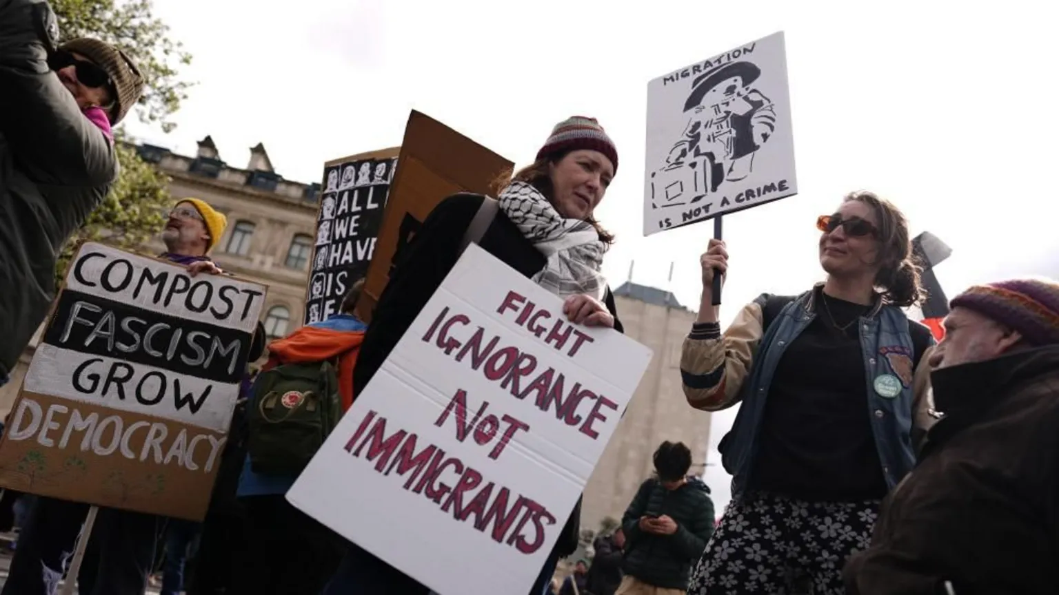 PA A woman holds a poster reading 'fight ignorance not immigrants' and another woman next to her has a sign with 'migration is not a crime'.