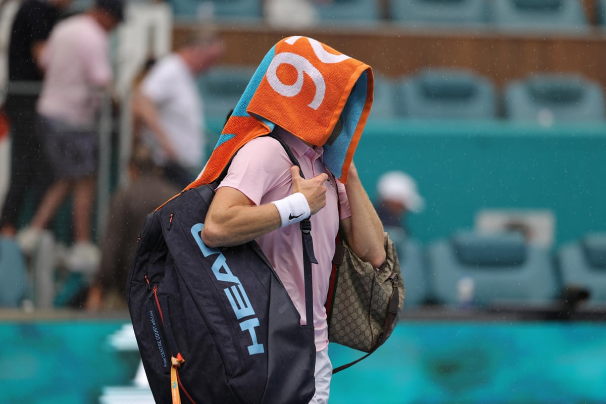 Jannik Sinner walks off court as play is stopped due to rain.