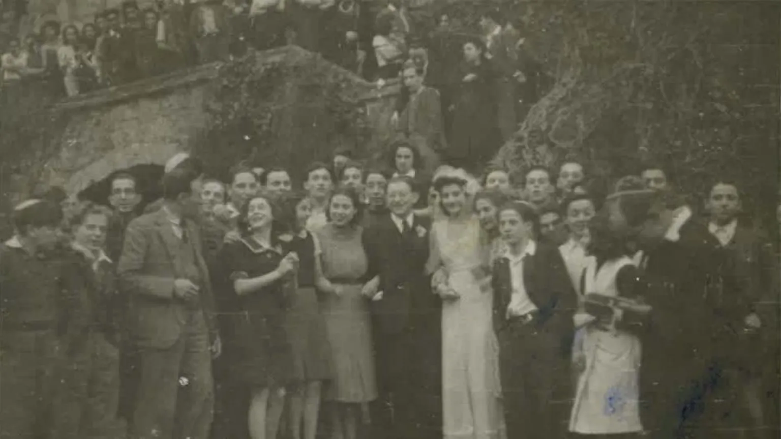 Gwrych Castle Trust Archive Black and white picture of people standing by the garden steps of the castle. Among the people is a bride and groom, wearing a wedding dress and suit