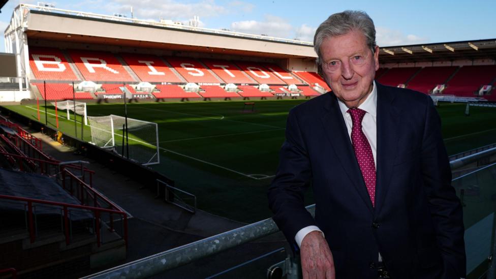 Roy Hodgson standing with a view inside Ashton Gate Stadium behind him and the word BRISTOL displayed on the stand seats 