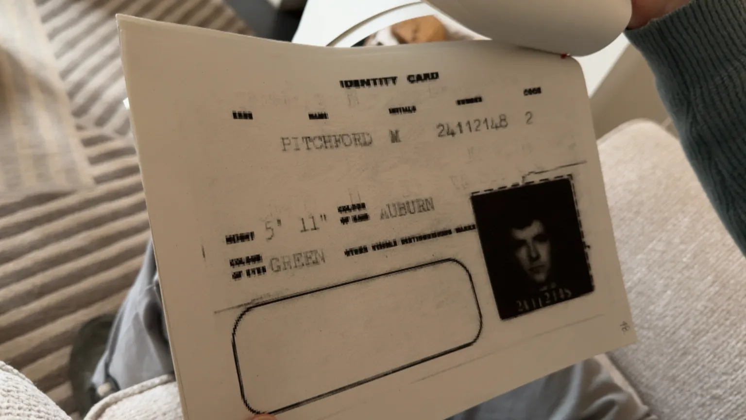 A close up image of a page within a pile of documents being held by Michael which shows a blurry copy of his military ID card.