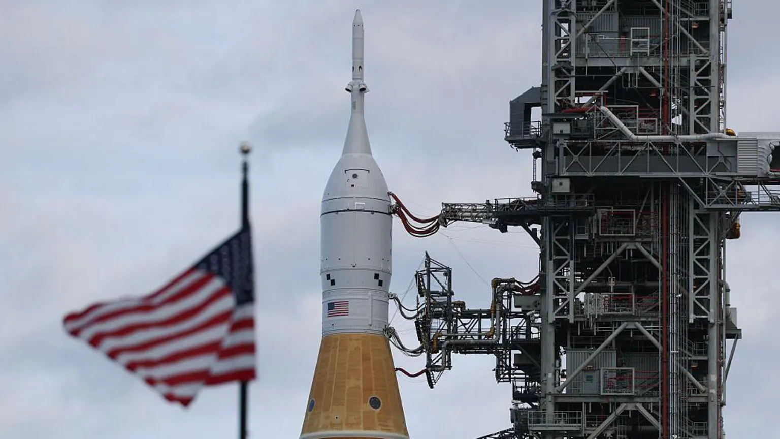 Joe Raedle/ NASA's Artemis II is rolled from the Vehicle Assembly Building at NASA’s Kennedy Space Center as the American flag sits in the foreground 