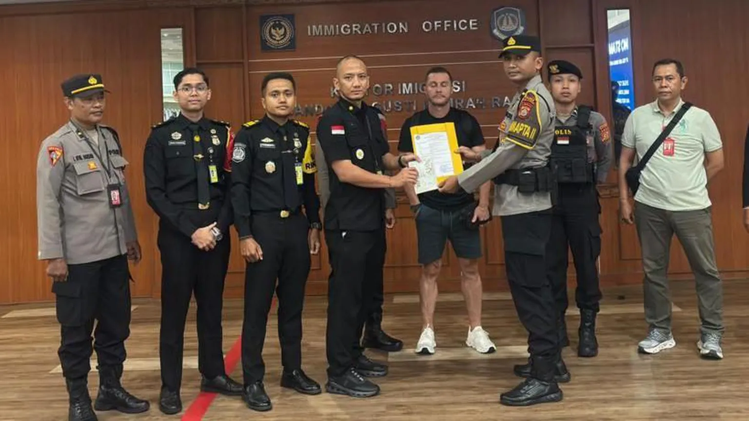 Ngurah Rai Immigration Office Steven Lyons flanked by police officers