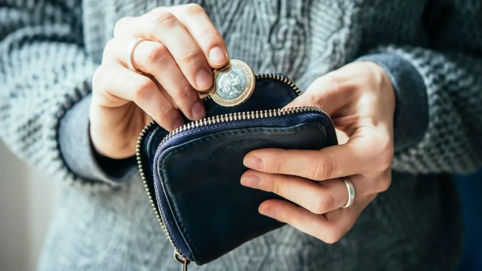 Getty Women holding a purse and a one pound coin.