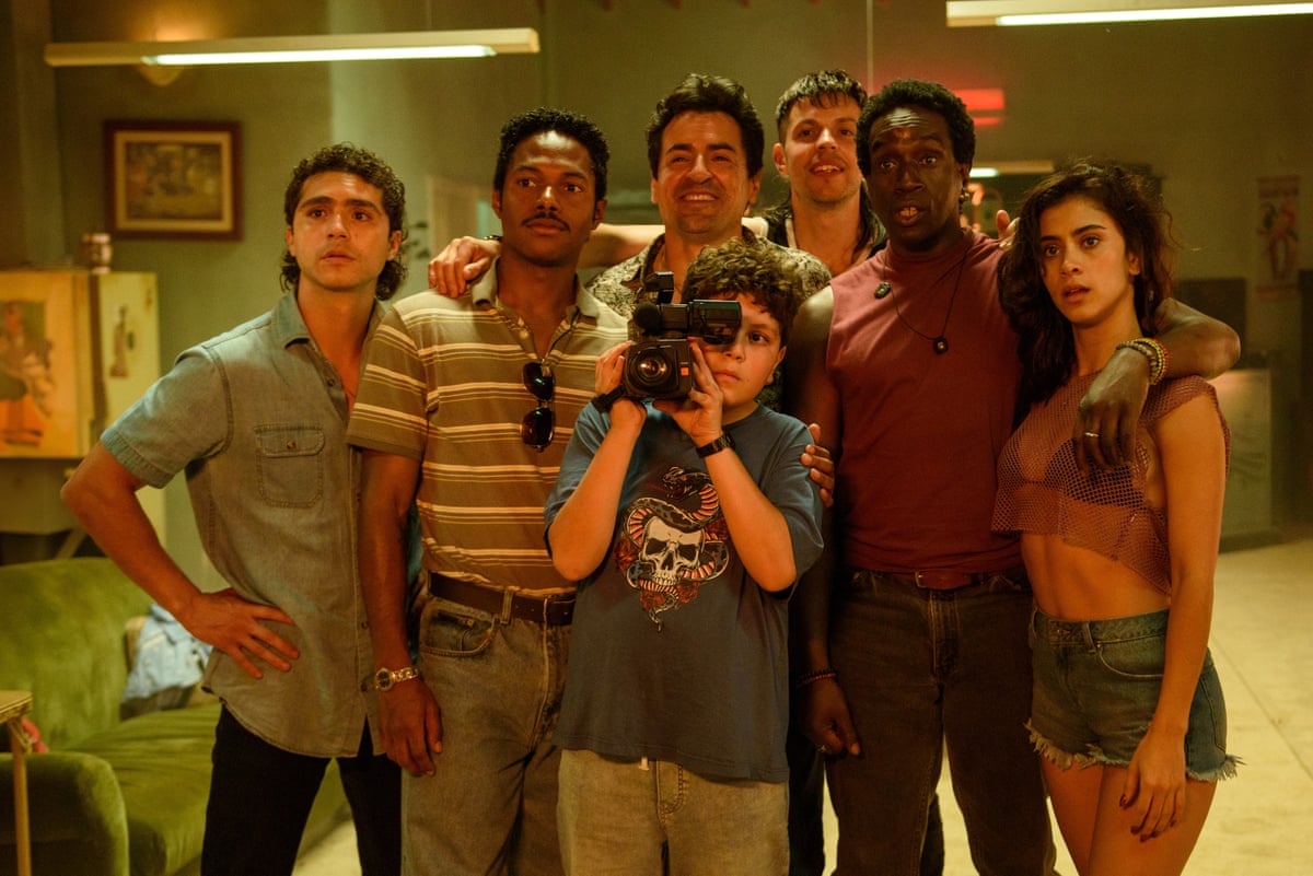 A group of young people surround a young boy holding a video camera