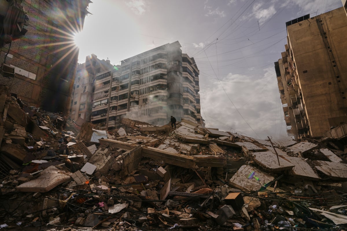 A man stands atop a pile of rubble from a destroyed building.