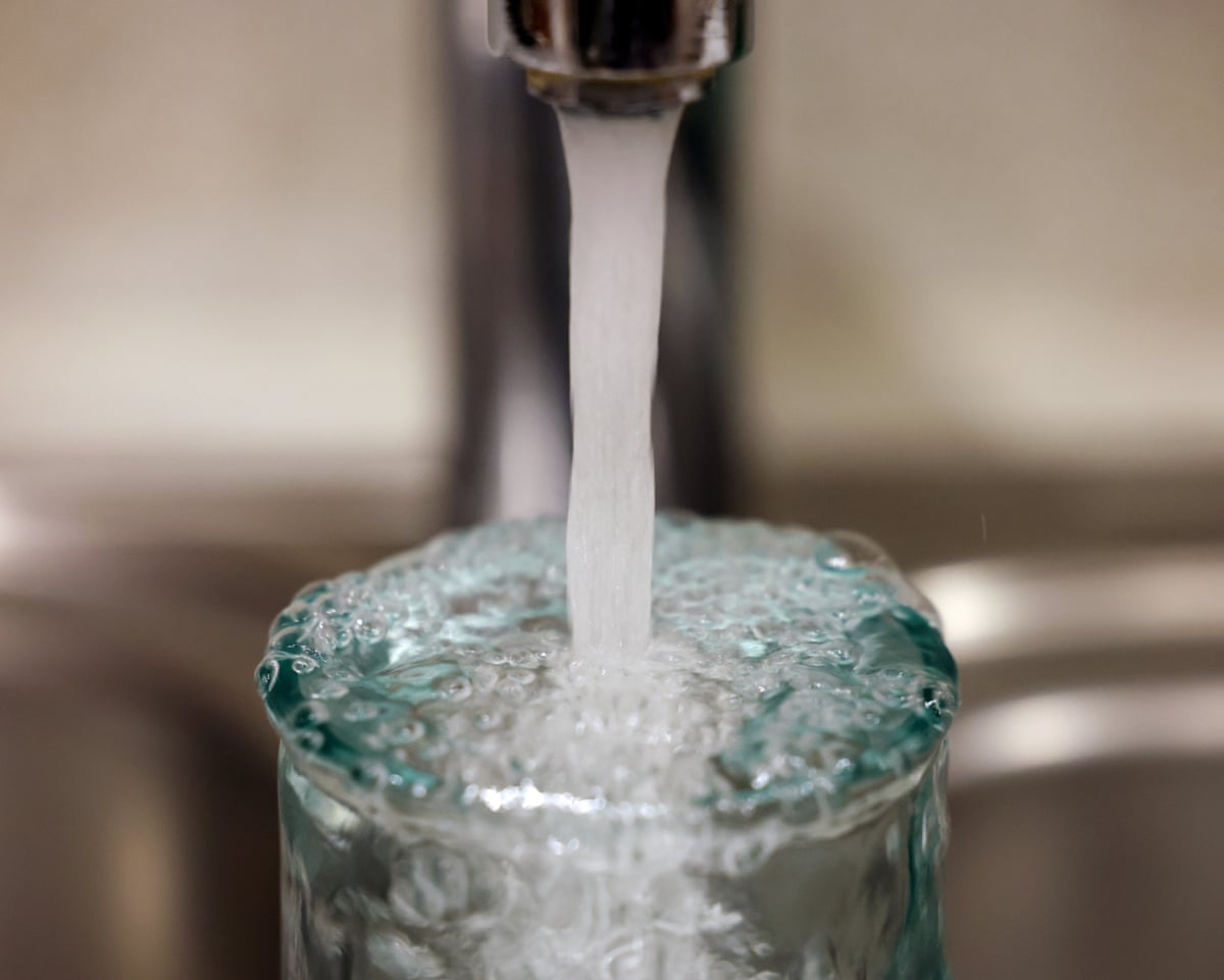 A close-up of a glass overflowing as as it is filled up with water from a tap