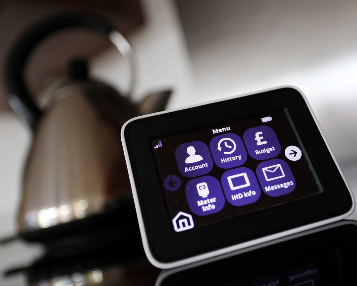 An energy smart meter on the sideboard of a kitchen in front of a metal kettle