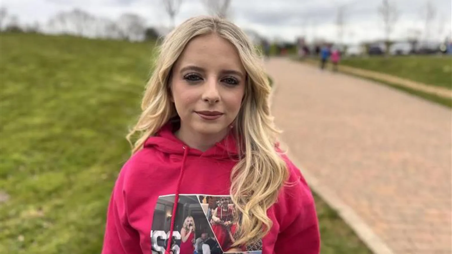 Megan Carlile pictured with shoulder length blonde hair and wearing a pink hoodie with pictures of herself and Amelia.