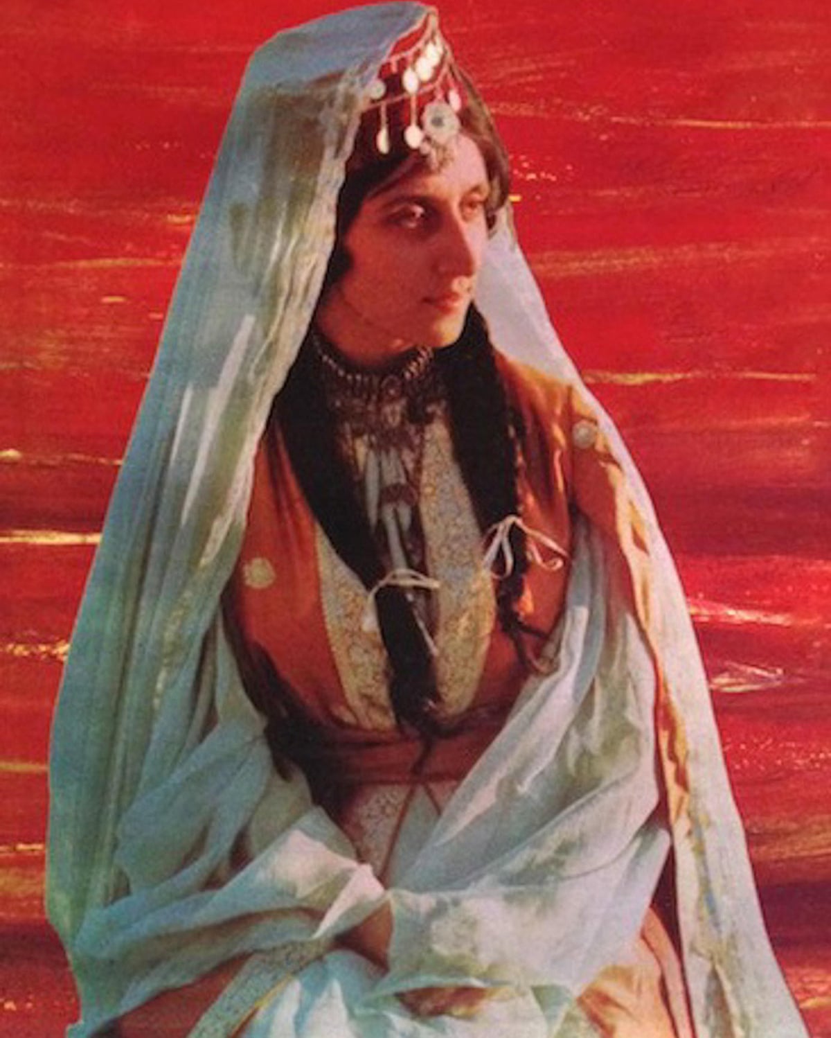 The singer Fairuz sitting against a red background