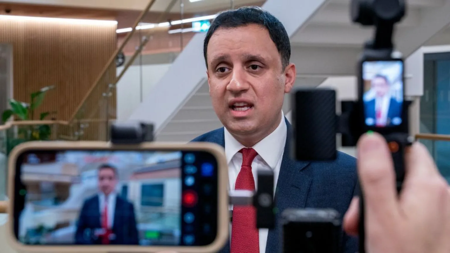 Anas Sarwar, who has short black hair, speaks to the media while wearing a business suit