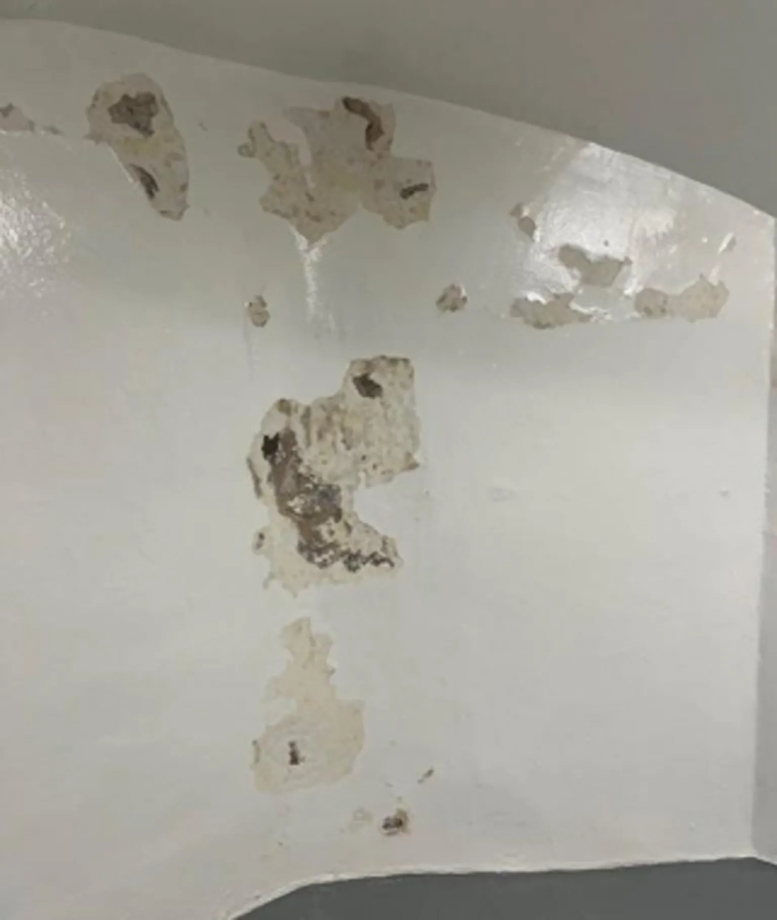 HMIPS Chipped and broken plaster on the white wall of a cell in a custody unit